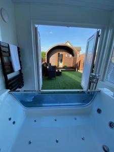 a tub in a bathroom with a view of a yard at Highland Stays - Ben View Studio Pod & Jacuzzi Bath in Fort William