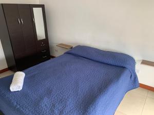 Un dormitorio con una cama azul con una toalla. en Apartamento cerca del CC Titan Plaza, en Bogotá