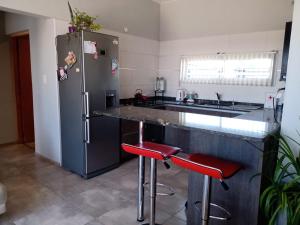 a kitchen with a stainless steel refrigerator and red stools at Mi casa es tu casa!! in Malargüe