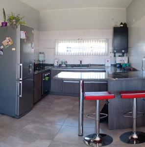 uma cozinha com um frigorífico e 2 bancos de bar em Mi casa es tu casa!! em Malargüe