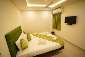 a bedroom with a bed with a green headboard and a television at SAARA INN in Pondicherry