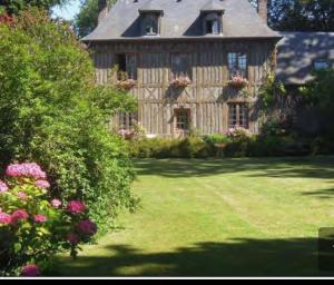 a large wooden house with flowers in a yard at LA MAISON DE LALETTE - B&B et Workshop Photo durant la belle saison - in Gruchet-Saint-Siméon