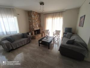 a living room with two couches and a fireplace at VILLA ALKMINI NEAR THE AIRPORT in Vravrona