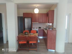 a kitchen with wooden cabinets and a table and chairs at VILLA ALKMINI NEAR THE AIRPORT in Vravrona