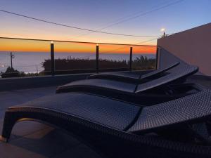 a row of chairs sitting on top of a building with a sunset at Calheta Ocean View Apartment 2 - Air Condition in Estreito da Calheta