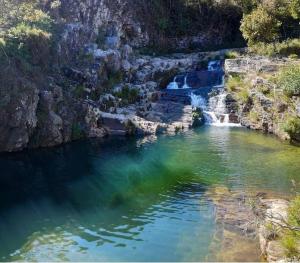 a body of water with a waterfall in the background at Pousada e Restaurante Boia Cross in Vargem Bonita