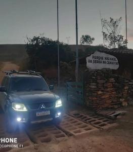 ein Auto, das neben einer Steinmauer mit eingeschaltetem Licht parkt in der Unterkunft Pousada e Restaurante Boia Cross in Vargem Bonita