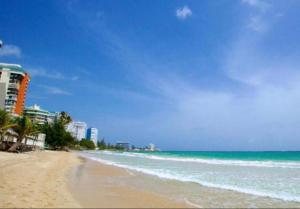 a sandy beach with buildings and the ocean at Mar Báltico in San Juan