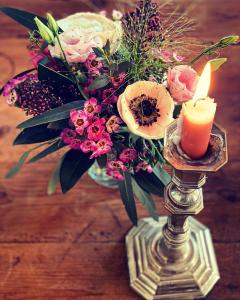 een vaas van bloemen met een kaars op een tafel bij Le Clos de Bénédicte in Bondues