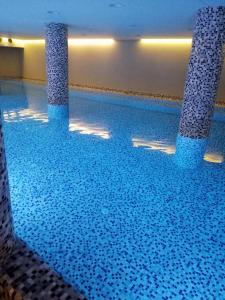 a large swimming pool with blue tiles on the floor at Pegaz009**** in Vrnjačka Banja