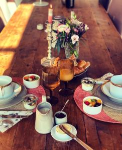 una mesa de madera con tazas y platos de comida. en Le Clos de Bénédicte, en Bondues