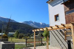 a wooden pergola in front of a house with mountains at Origen Rent a house in El Bolsón +4 photos