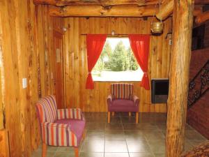 a living room with two chairs and a window at Las Cuatro Lunas in Lago Meliquina