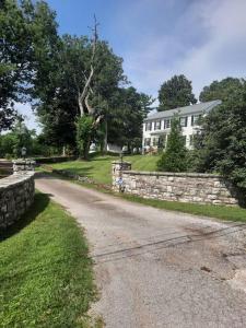 a road leading to a house with a stone wall at Charming Cottage on a City Farm! in Lexington