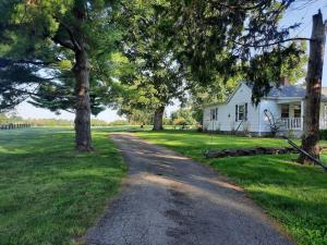a road in front of a white house with trees at Charming Cottage on a City Farm! in Lexington +12 photos