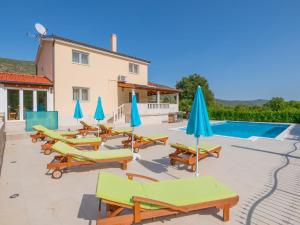 a group of lounge chairs and umbrellas next to a pool at Villa Secret Beauty with Saltwater Pool in Imotski