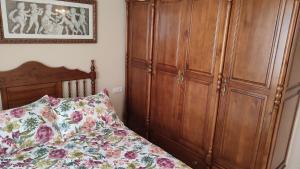 - une chambre avec un lit et une grande armoire en bois dans l'établissement Apartamento Paseo Marítimo, Centro Torre del Mar, à Torre del Mar
