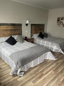 two beds in a room with wooden floors at Motel Valois YL inc in Acton Vale