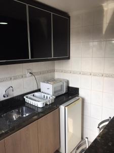 a kitchen with a sink and a microwave on a counter at Flat ao lado do Shopping in Santa Cruz do Sul