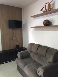 a living room with a couch and a flat screen tv at Flat ao lado do Shopping in Santa Cruz do Sul