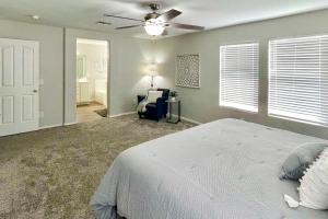 a bedroom with a bed and a chair and a ceiling fan at Game Room and Pool Spacious Queen Creek Home! in Queen Creek