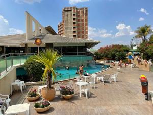 una piscina con mesas y sillas y un edificio en Araras Apart Service I, en Caldas Novas