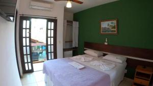 a bedroom with a bed with a green wall at Pousada Parcel das Ilhas in Barra do Sahy