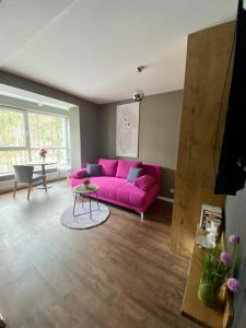 een woonkamer met een roze bank en een tafel bij Apartament SPA 44 Resort Kozubnik blisko Szczyrk- 5D Apartamenty in Porąbka