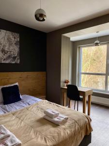 een slaapkamer met een bed, een bureau en een raam bij Apartament SPA 44 Resort Kozubnik blisko Szczyrk- 5D Apartamenty in Porąbka