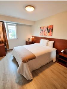 Un dormitorio con una gran cama blanca y una ventana en Hotel Las Palmas, en Lima
