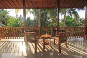 a wooden porch with a table and chairs on it at Mahanadewi Villa in Ubud