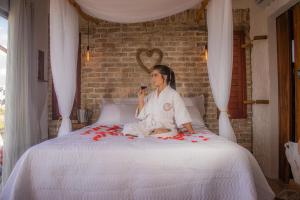 a woman sitting on a bed with a glass of wine at Chalé Formoso - Chalé Romântico com Hidromassagem in Serra de São Bento