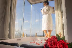 a woman standing in a bath tub in a window at Chalé Formoso - Chalé Romântico com Hidromassagem in Serra de São Bento
