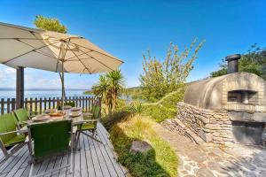 a patio with a table and an umbrella and an oven at Wai Marino - Taupo in Taupo