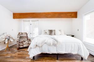 ein Schlafzimmer mit einem weißen Bett und einem Stuhl in der Unterkunft Falke Inn in Anchorage