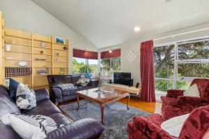 a living room with couches and a table at Francis Orchard Country Stay - Waipu Holiday Home in Waipu Cove