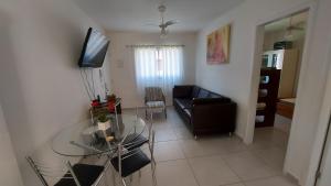 uma sala de estar com uma mesa de vidro e uma televisão em Apartamento Boracéia Bertioga em Bertioga