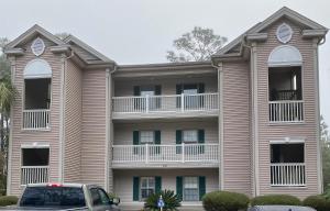 um prédio de apartamentos com um carro estacionado em frente em True Blue Hideaway em Pawleys Island