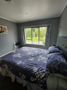 um quarto com uma cama com um edredão azul e uma janela em Quiet Waters em Ohaeawai