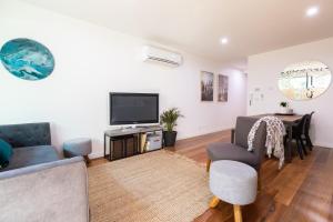 ein Wohnzimmer mit einem TV und einem Tisch in der Unterkunft Experience Port Melbourne in Melbourne