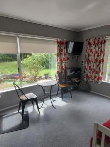 a living room with a table and chairs and a window at Quiet Waters in Ohaeawai