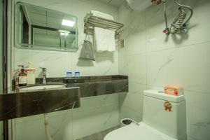 a bathroom with a sink and a toilet and a mirror at Locals Apartment Place 44 in Zhanjiang +18 photos