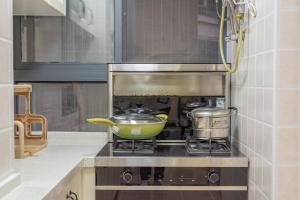 una cocina con fogones, una sartén verde y 2 ollas en Locals Apartment Inn 01, en Ganzhou