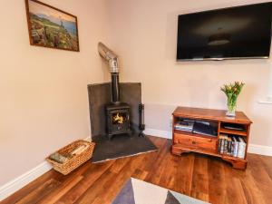 a living room with a wood stove and a tv at Baywood Cottage in Keighley