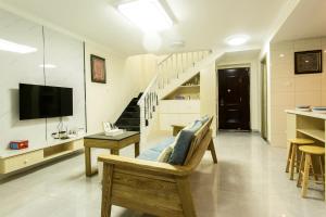 een woonkamer met een bank, een televisie en een trap bij Locals Apartment House 19 in Zhenhai