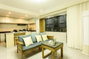 a living room with a blue couch and a kitchen at Locals Apartment House 19 in Zhenhai