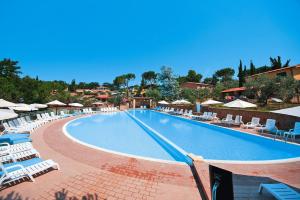 a large swimming pool with lounge chairs and umbrellas at Apartment in the Centra Vacanze il Borgo resort in Guardistallo in Guardistallo