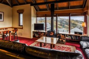 a living room with a leather couch and a table at Gundanora in Mount Hotham
