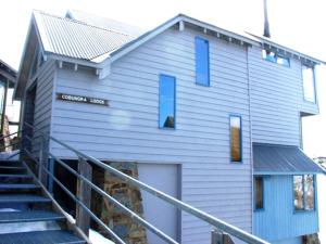 a house with blue windows and stairs in front of it at Cobungra in Mount Hotham