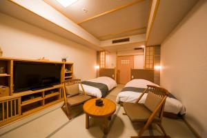 a room with two beds and a flat screen tv at Ikyu in Ise